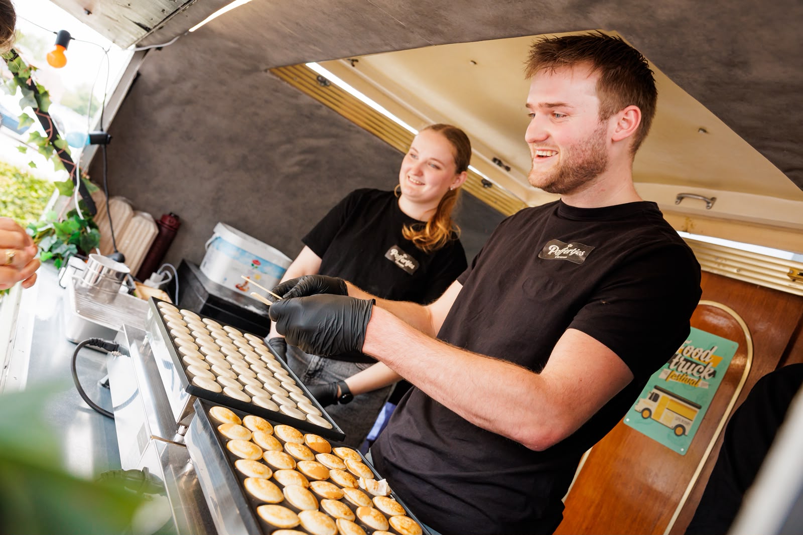 De eigenaar van De Poffertjes Caravan aan het bakken